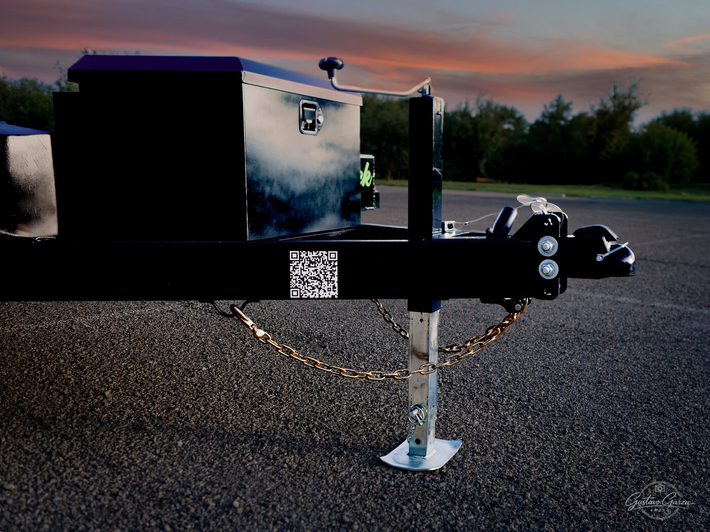 Trailer tongue at sunset with tool box, coupler, and drop-leg jack down